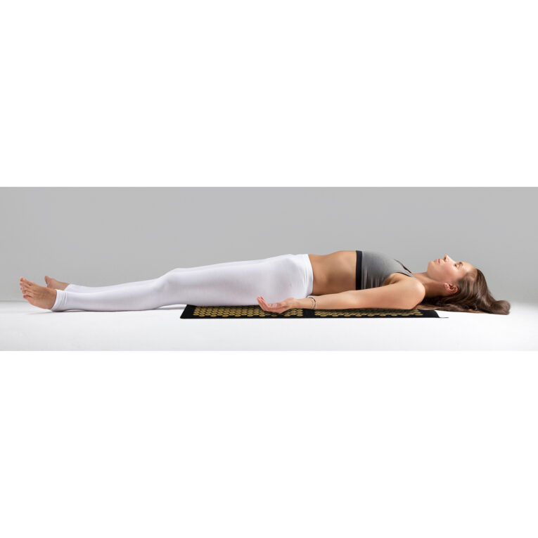 Young woman in Savasana pose, grey studio background